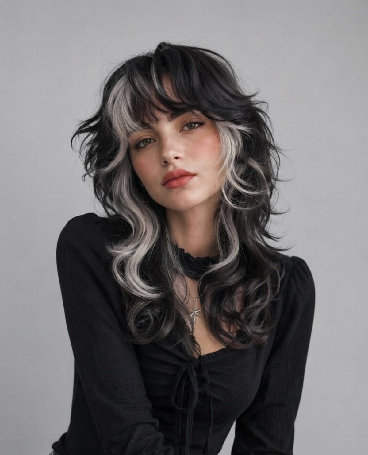 Woman with layered dark hair and bold silver-gray streaks framing her face