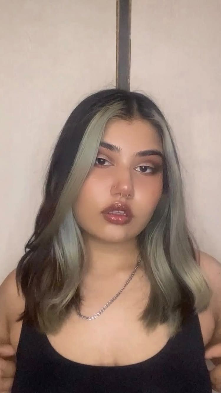 Dark center-parted hair features broad silver-gray face-framing accents