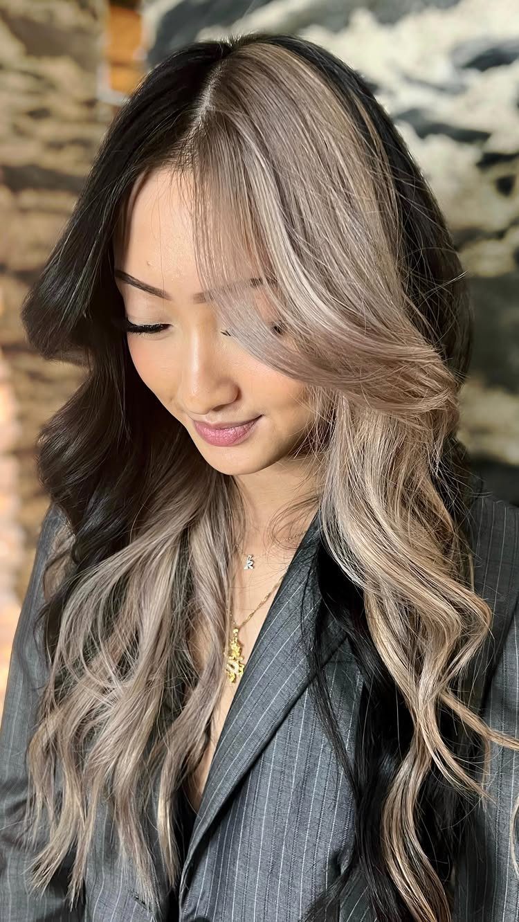 Woman wearing long dark hair with bold silver-gray block highlights