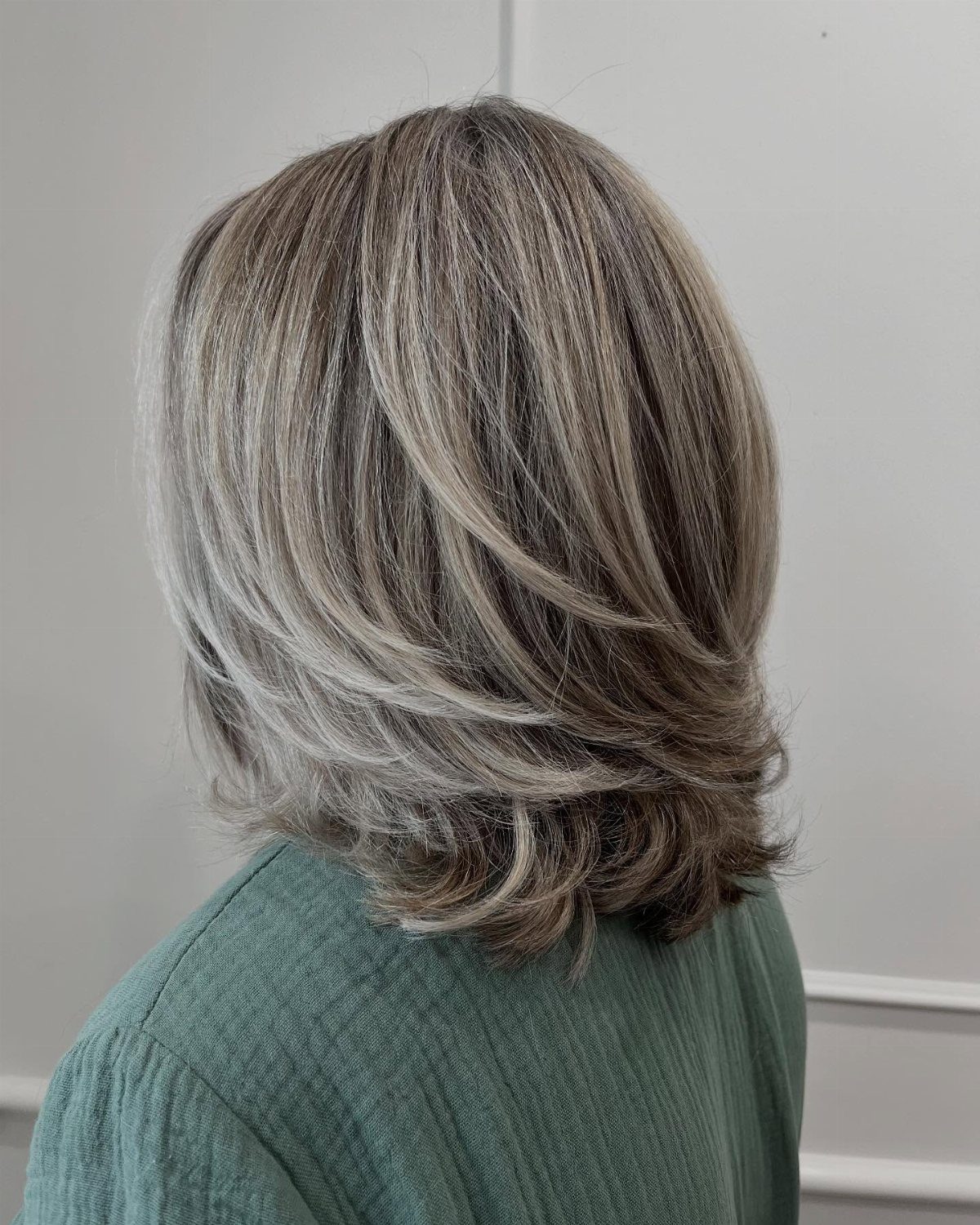 Layered gray-brown hair with silver highlights and a softly feathered finish