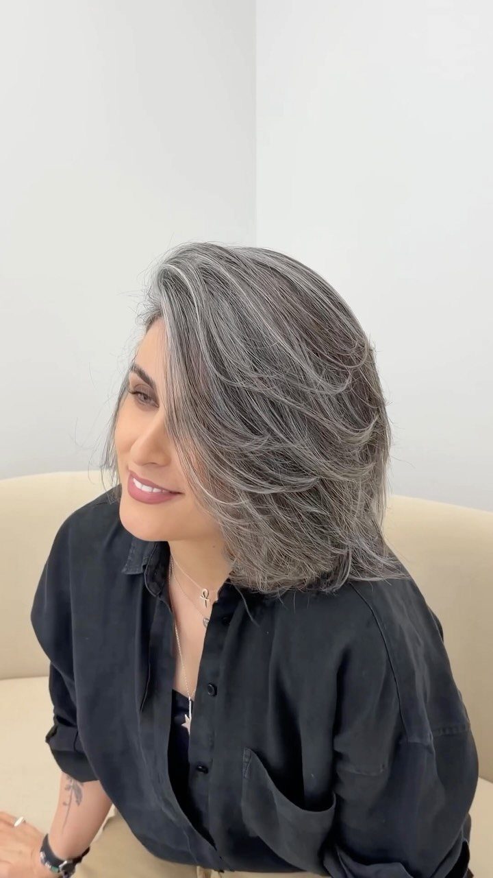 Woman with voluminous silver-grey hair styled in smooth, layered waves