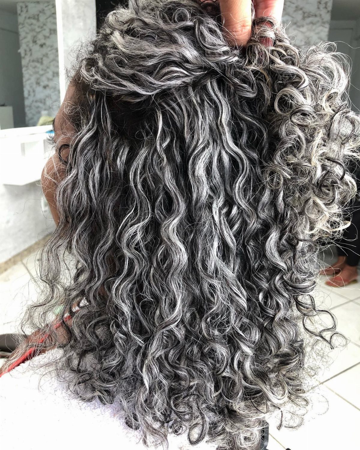 Long silver-grey curls with defined ringlets being lifted near the crown