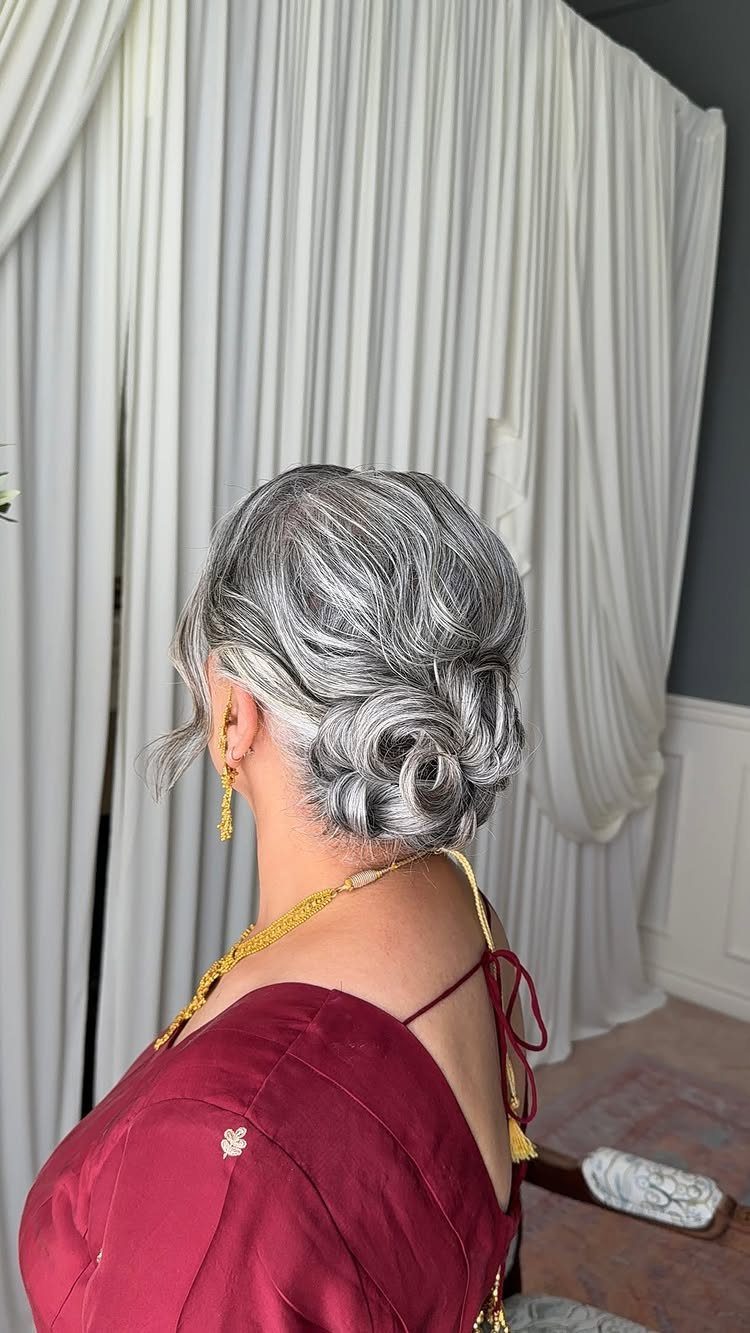 Silver-grey hair is twisted and pinned into an elegant low updo
