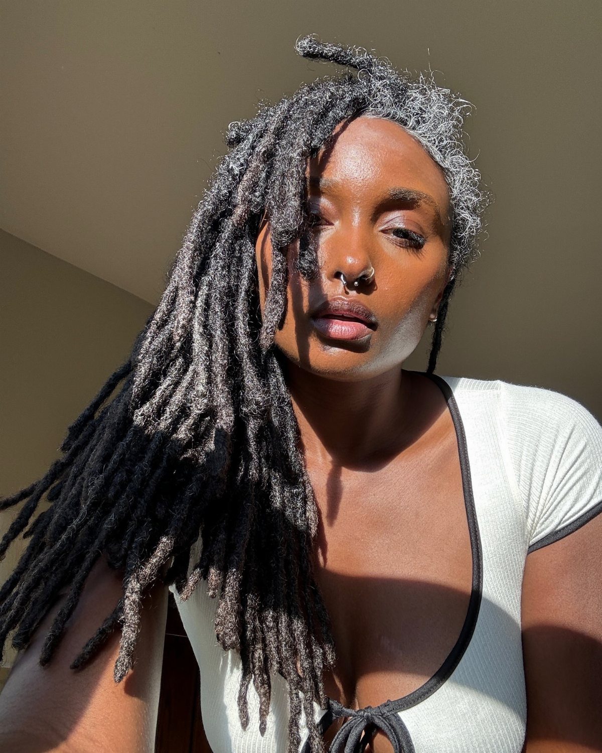 Woman with long blended grey and black locs draped over one shoulder