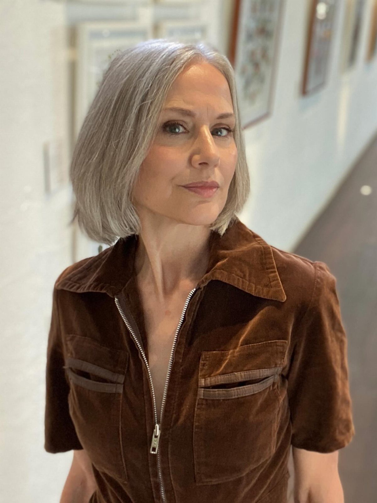 Woman posing with a smooth, chin-length silver-grey bob parted to the side