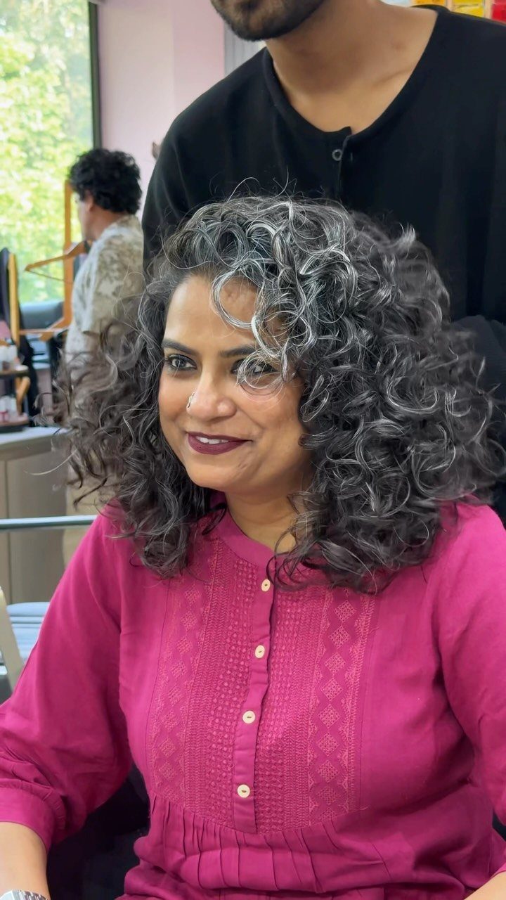 Woman with voluminous grey-streaked curls seated in a salon