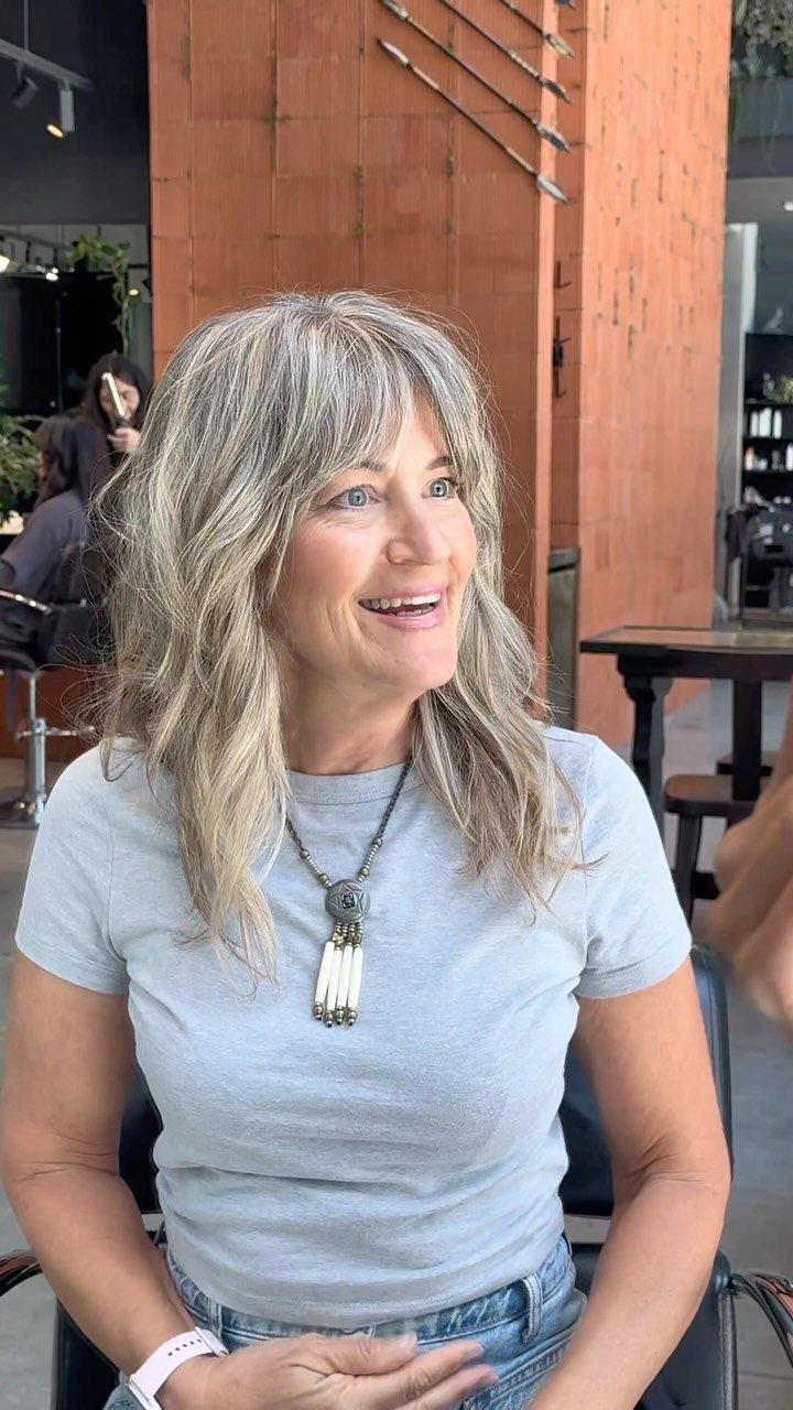 Woman with layered grey hair and bangs seated at an outdoor café
