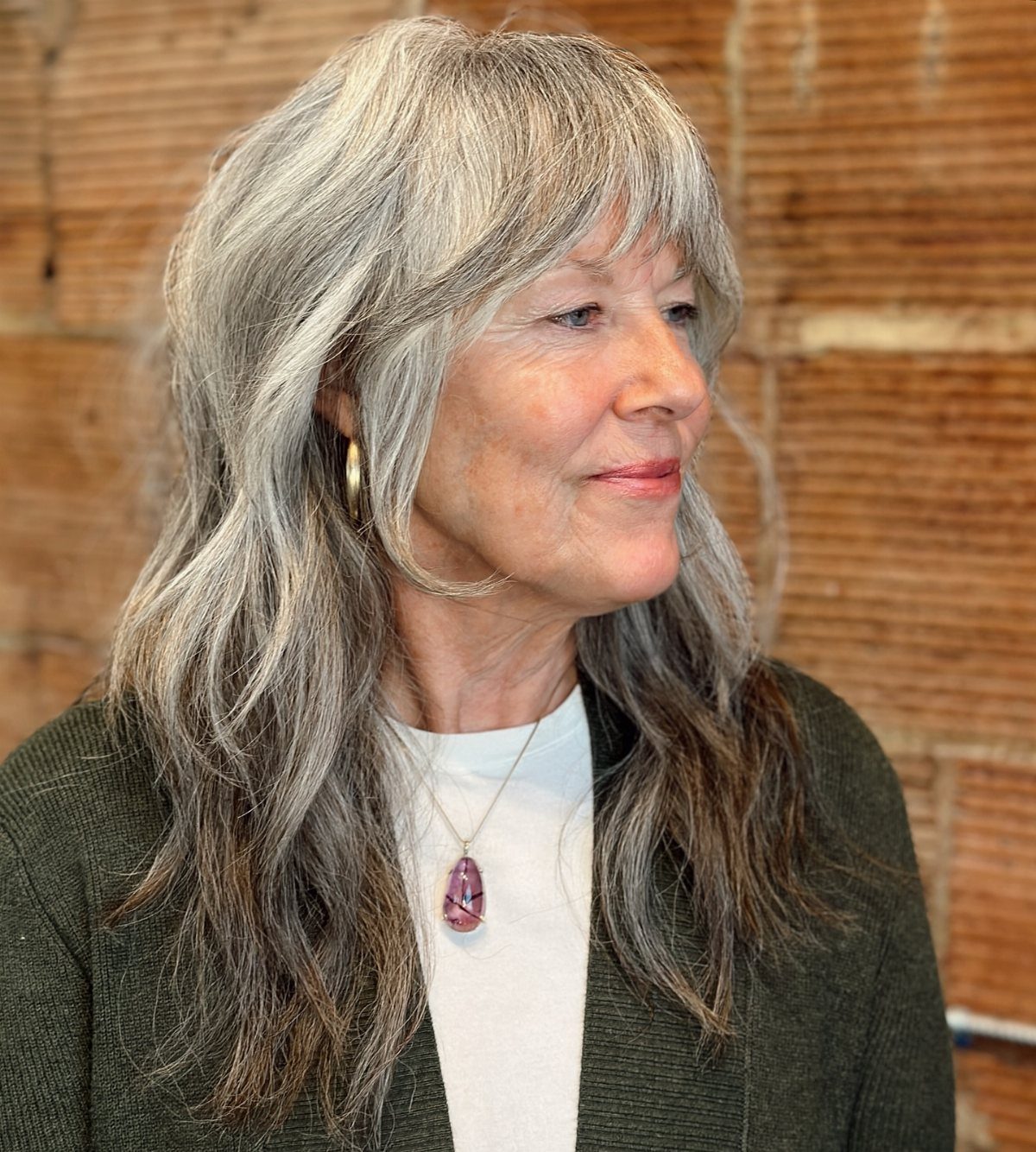 Older woman with long layered grey hair and a feathered fringe