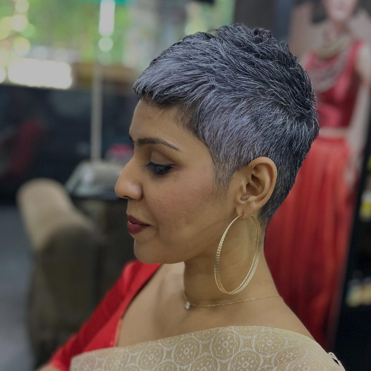 Woman showing a short, textured grey pixie cut in profile