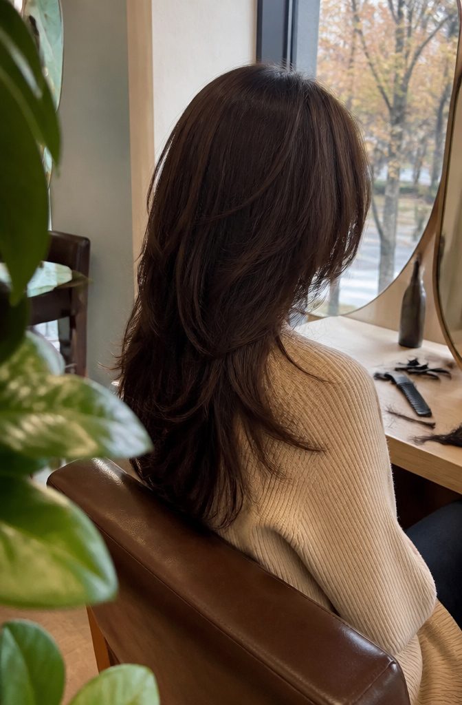 Long espresso hair with piecey layers beside a partially visible cheek