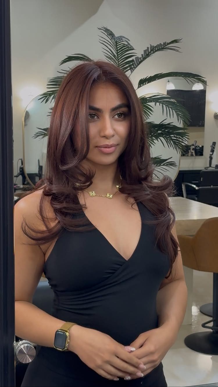 Woman with layered chocolate brown hair seated in a salon