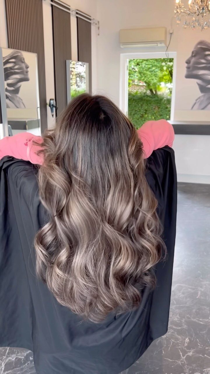 Long cool medium-brown waves displayed from behind in a salon chair