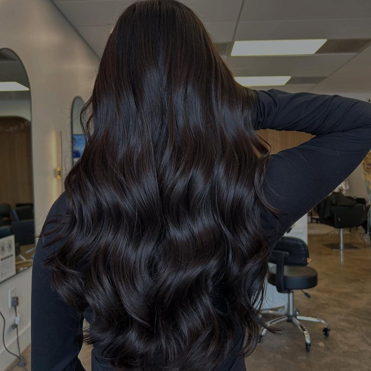 Long dark brown waves displayed from behind in a hair salon