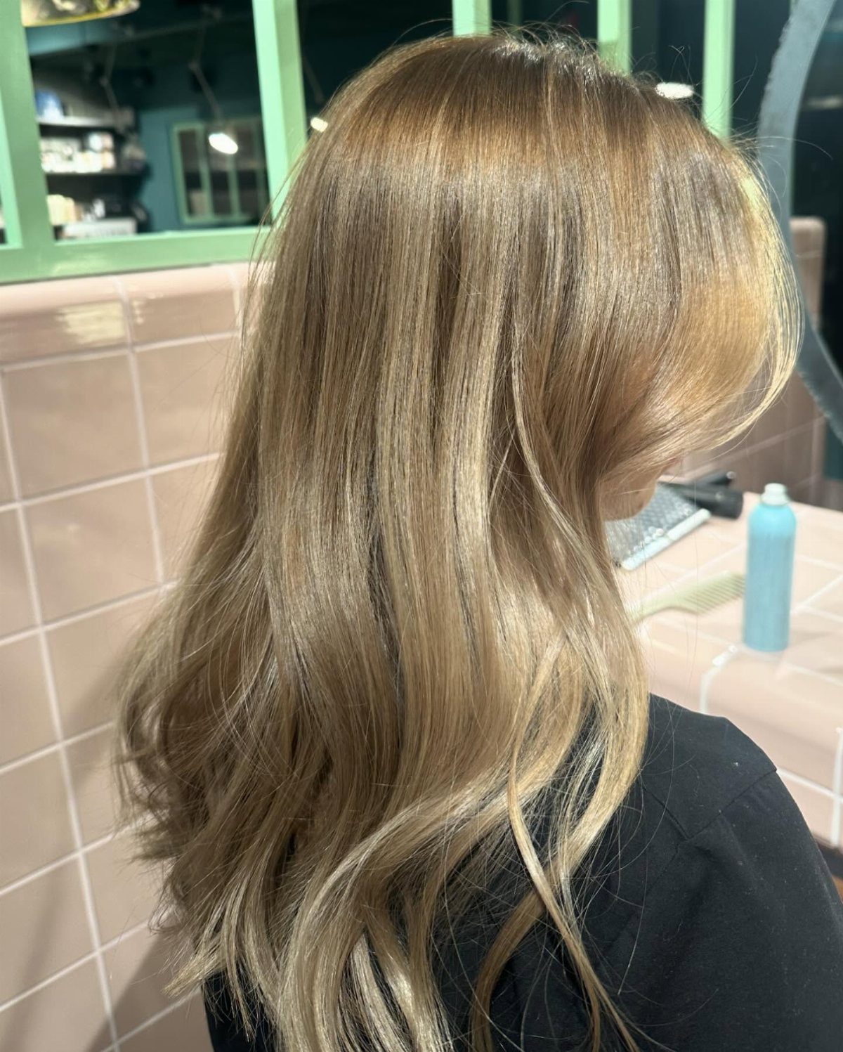Long wavy dirty blonde hair with blended beige-gold highlights in a salon
