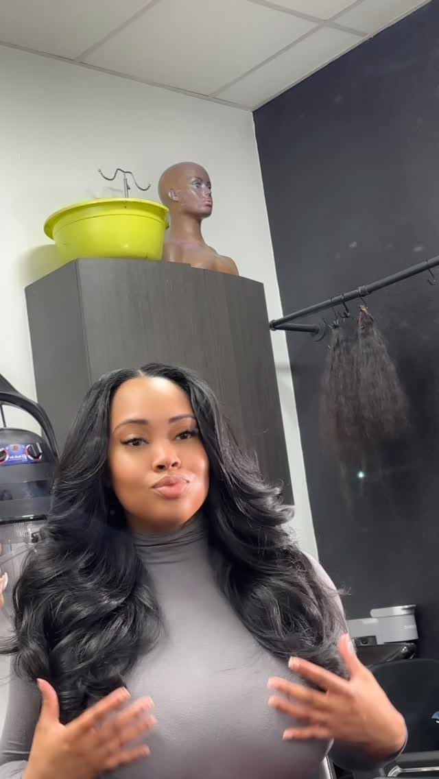 Woman posing with long, glossy jet-black hair in a salon