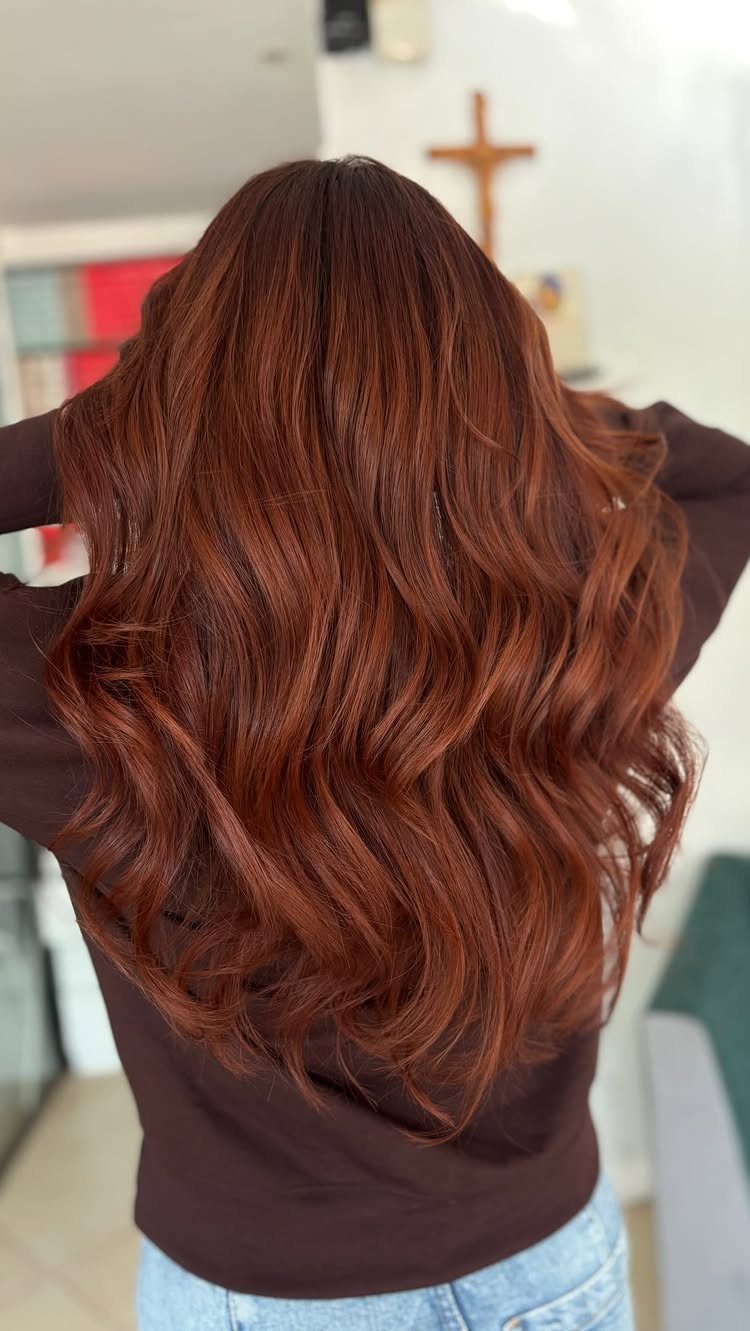 Long, wavy light auburn hair shown from behind in a bright room