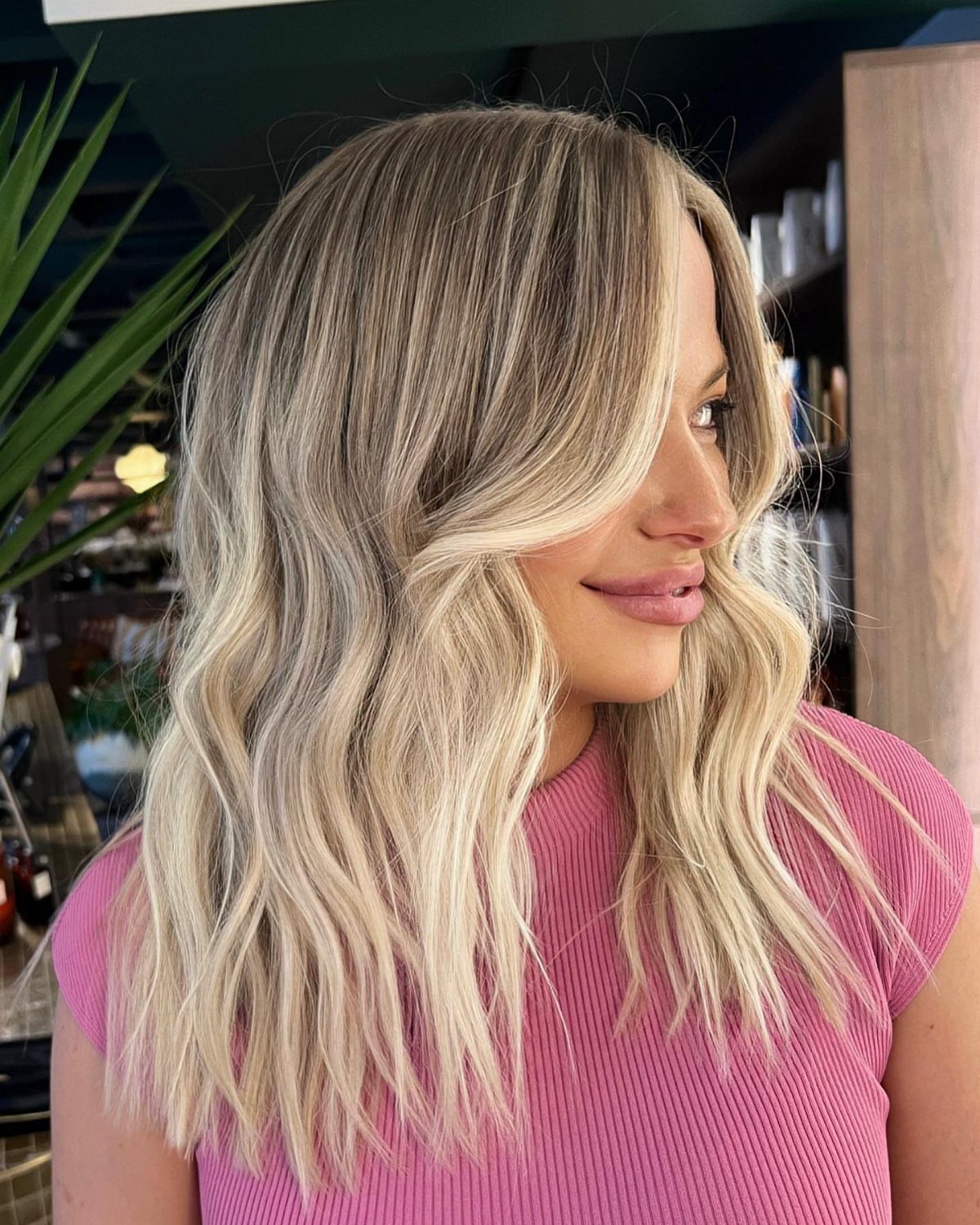 Wavy sandy blonde hair with darker roots and pale beige highlights