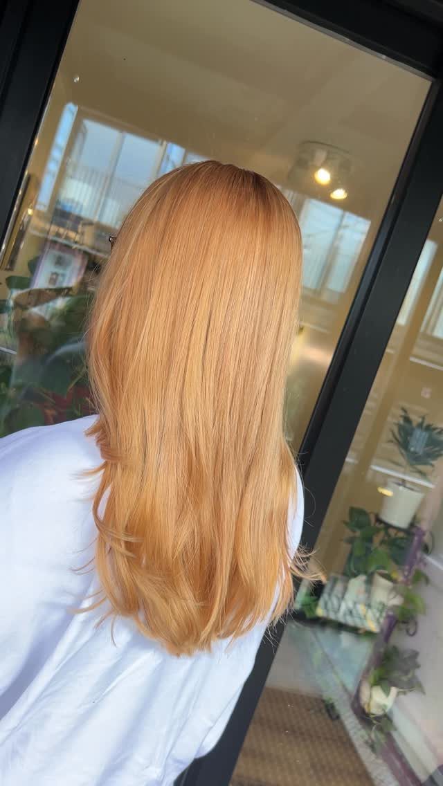 Strawberry-blonde hair falls straight to the shoulders with softly curled ends