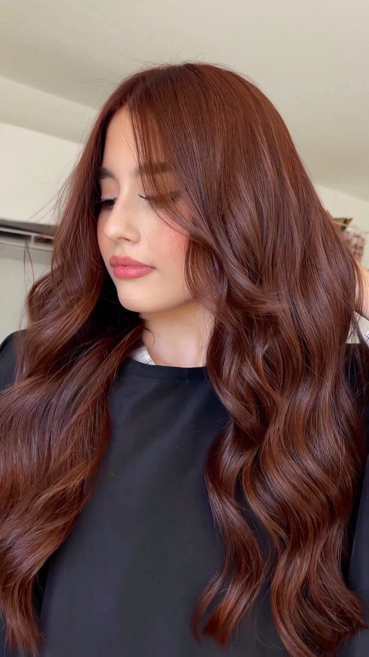 Woman with long, loose auburn red-brown waves and a black top