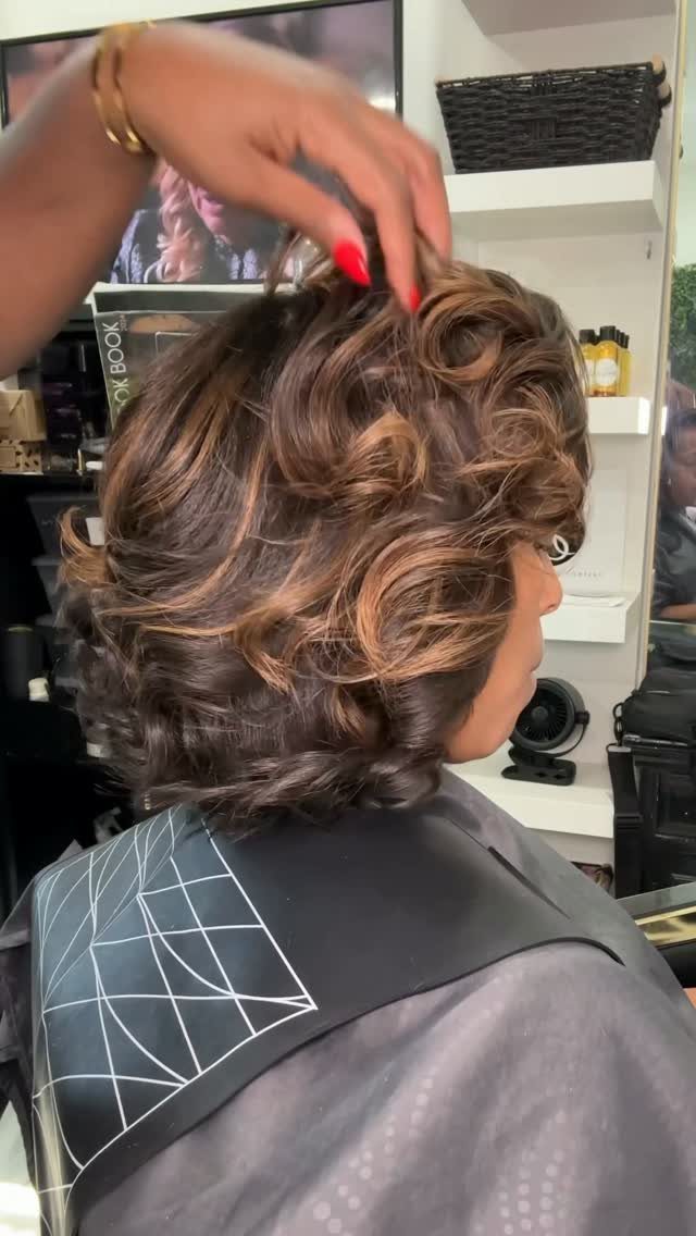 Glossy chestnut-brown curls styled with volume at a hair salon