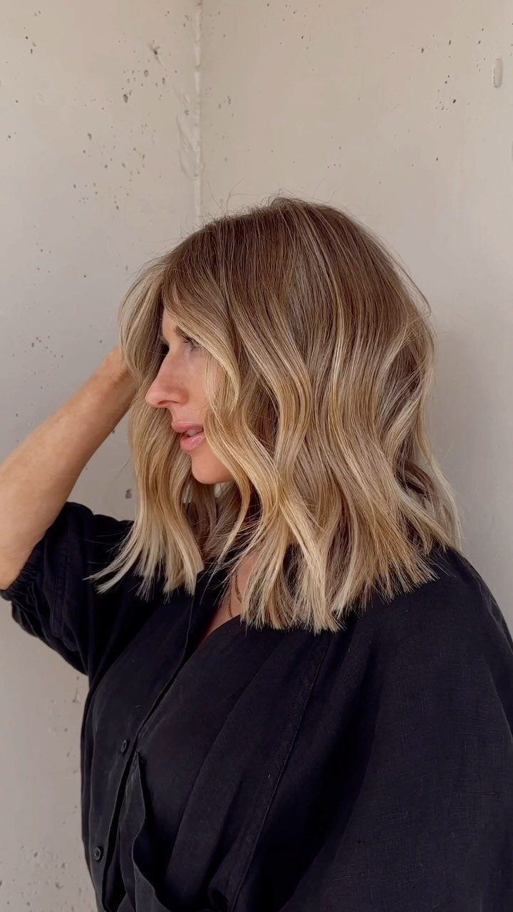 Woman with wavy blonde balayage and pale face-framing highlights