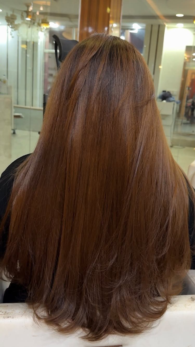 Long golden-brown hair falls smoothly with softly curled ends in a salon.