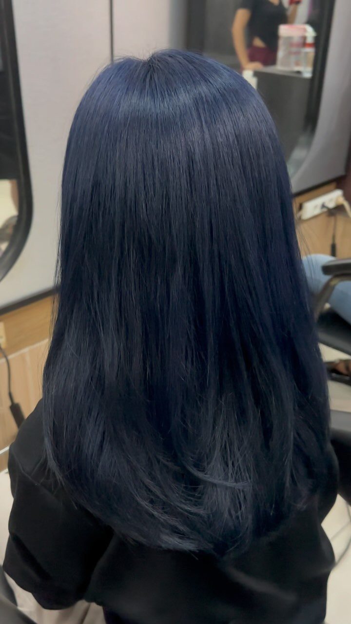 Long glossy midnight-black hair with subtle blue tones in a salon