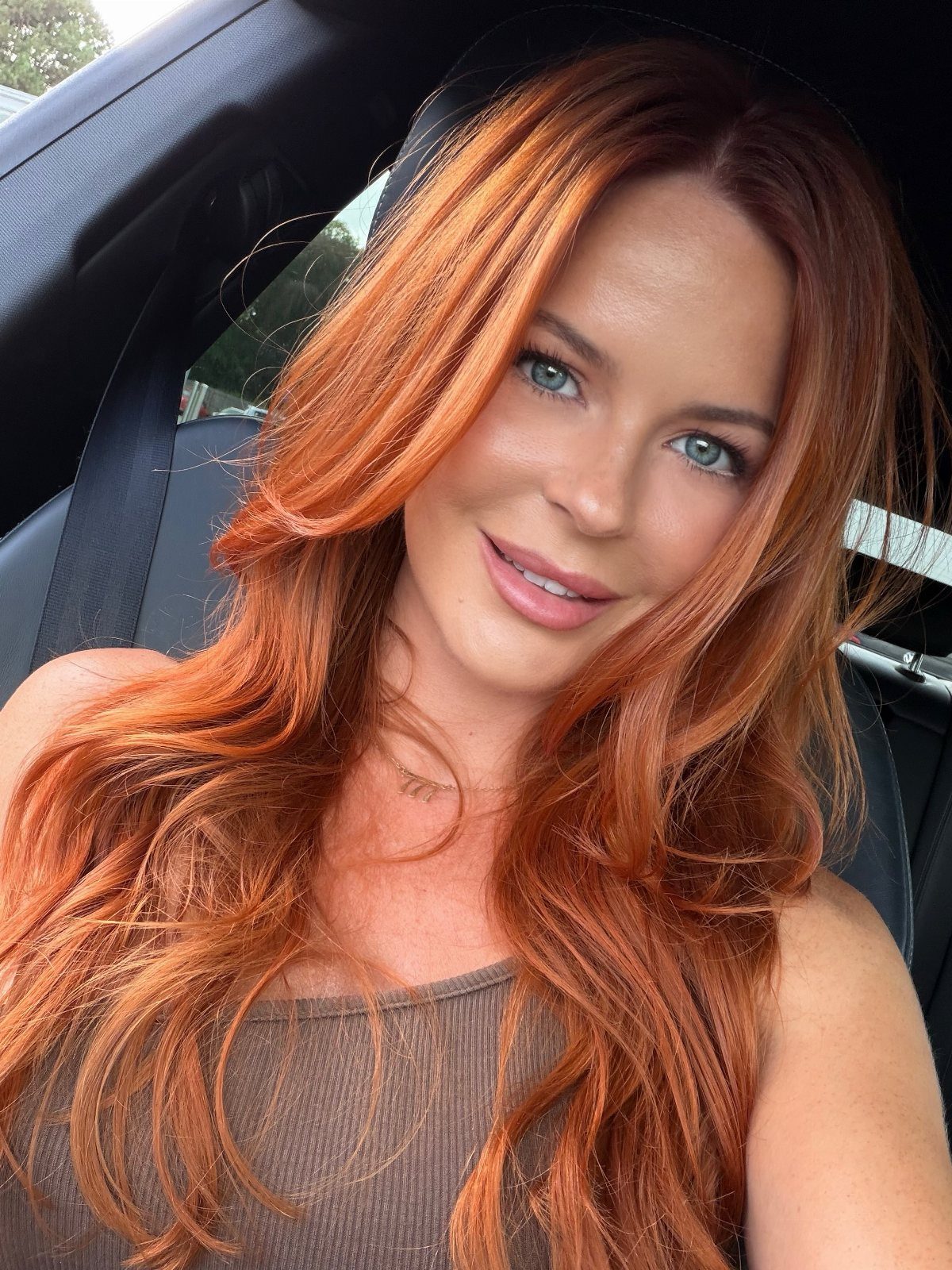 Woman with long vivid copper hair posing in a car