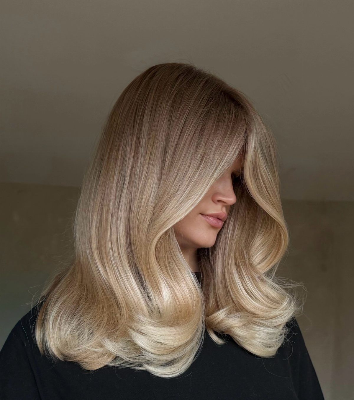 Woman with long beige blonde hair, darker roots, and soft warm highlights