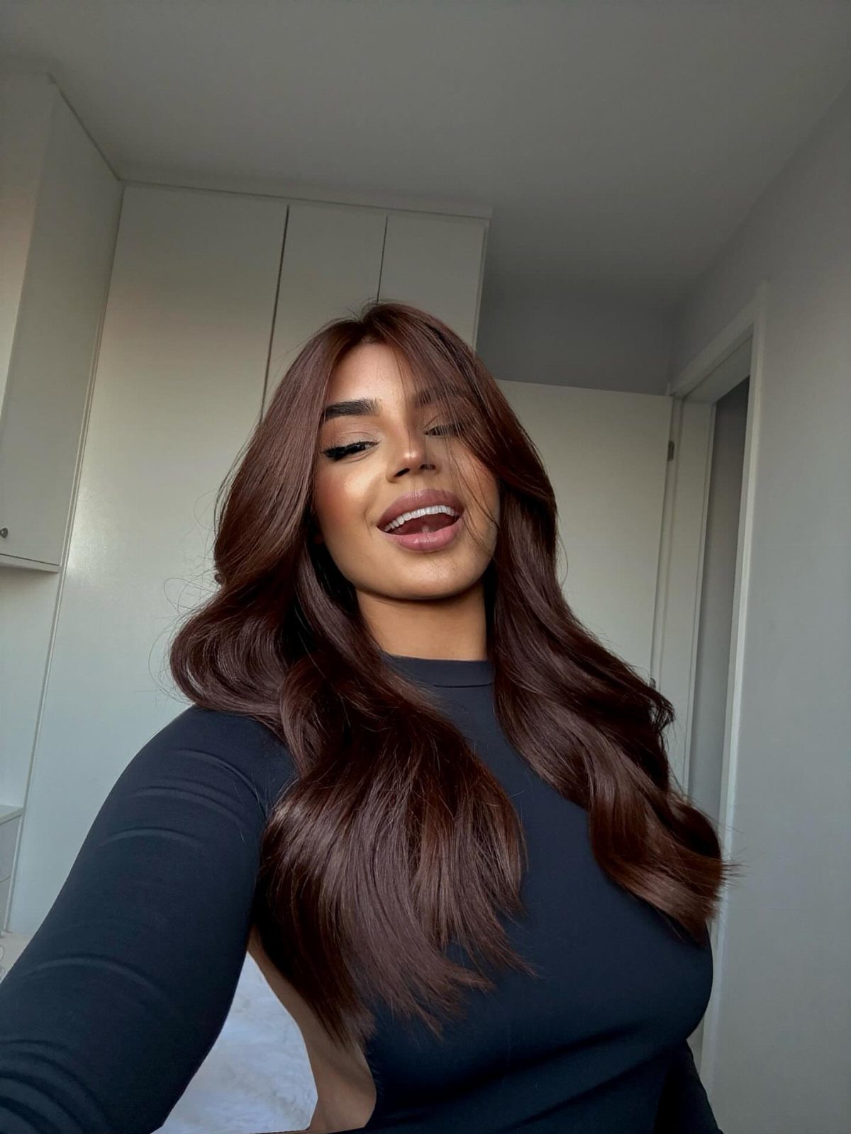 Woman posing with long, glossy chocolate-brown hair in loose waves