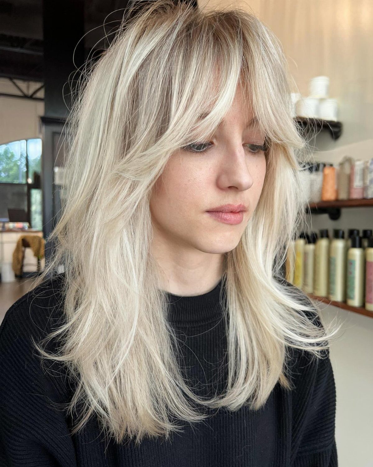 Pale platinum blonde layered hair with cool ashy tones against fair skin in a salon