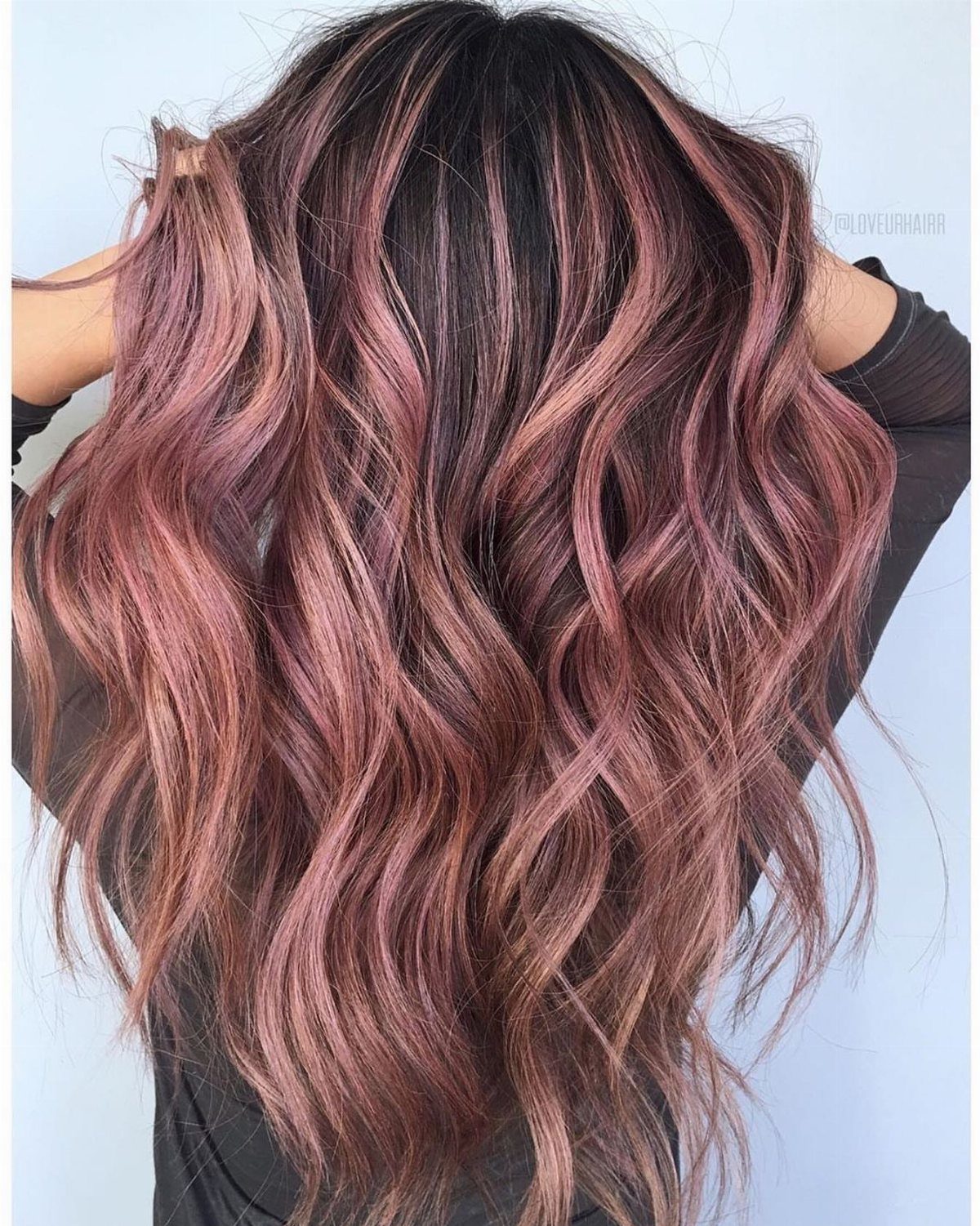Long wavy hair with dark roots and rose-gold pink highlights