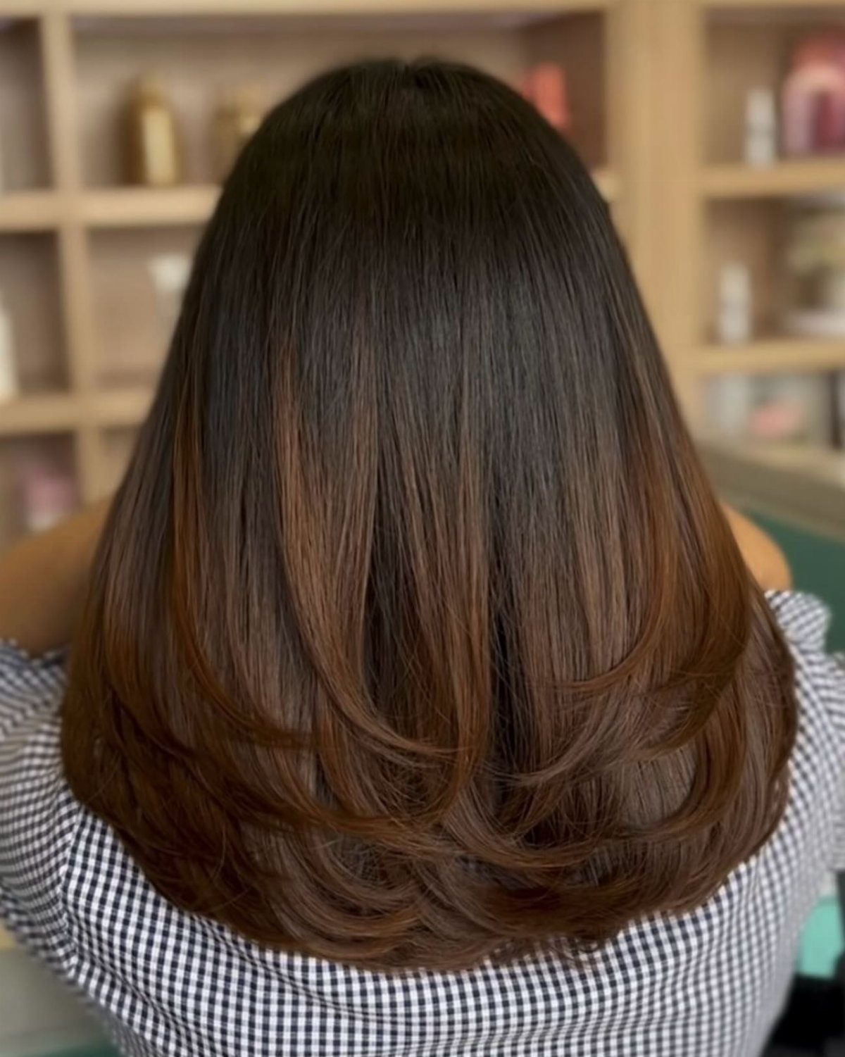 Dark brown hair transitions subtly to warmer, lighter brown curled ends