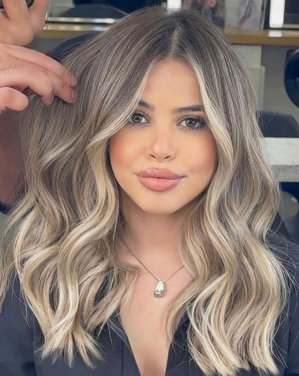 Woman showing wavy brunette hair blended into blonde balayage lengths