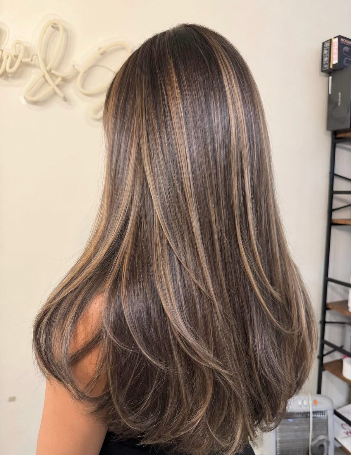 Long layered ash brown hair with silvery highlights and softly curled ends
