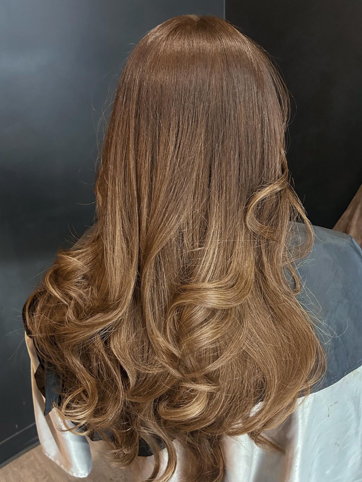 Long multi-tonal brown hair with golden highlights and voluminous curled ends