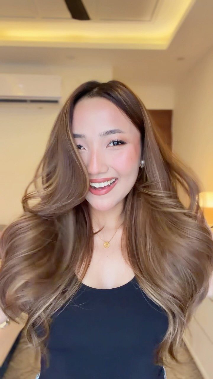 Woman with long, wavy honey light brown hair and golden highlights