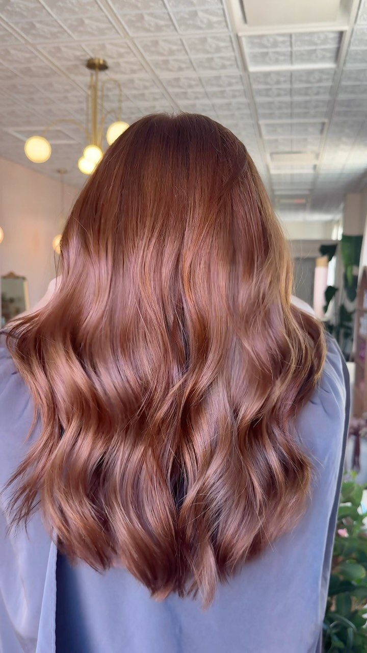 Long wavy light copper brown hair shown from behind in a salon