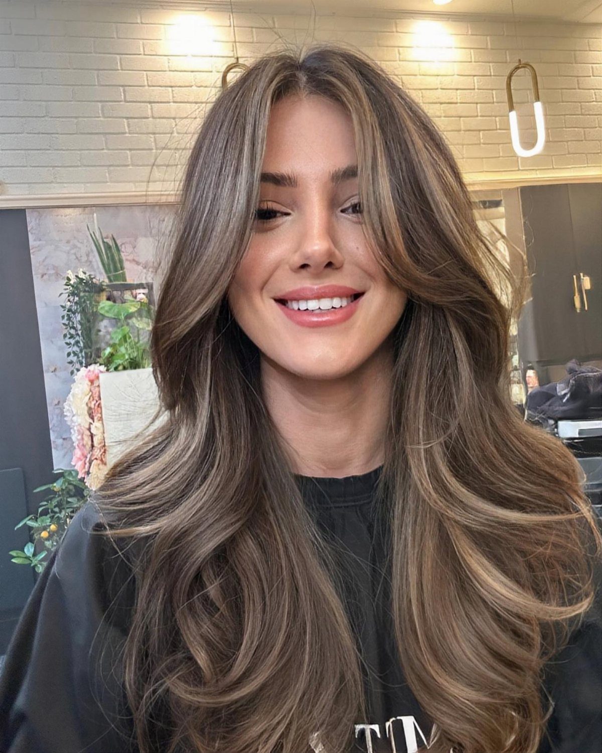 Woman showing long brunette hair with soft, lighter brown balayage pieces