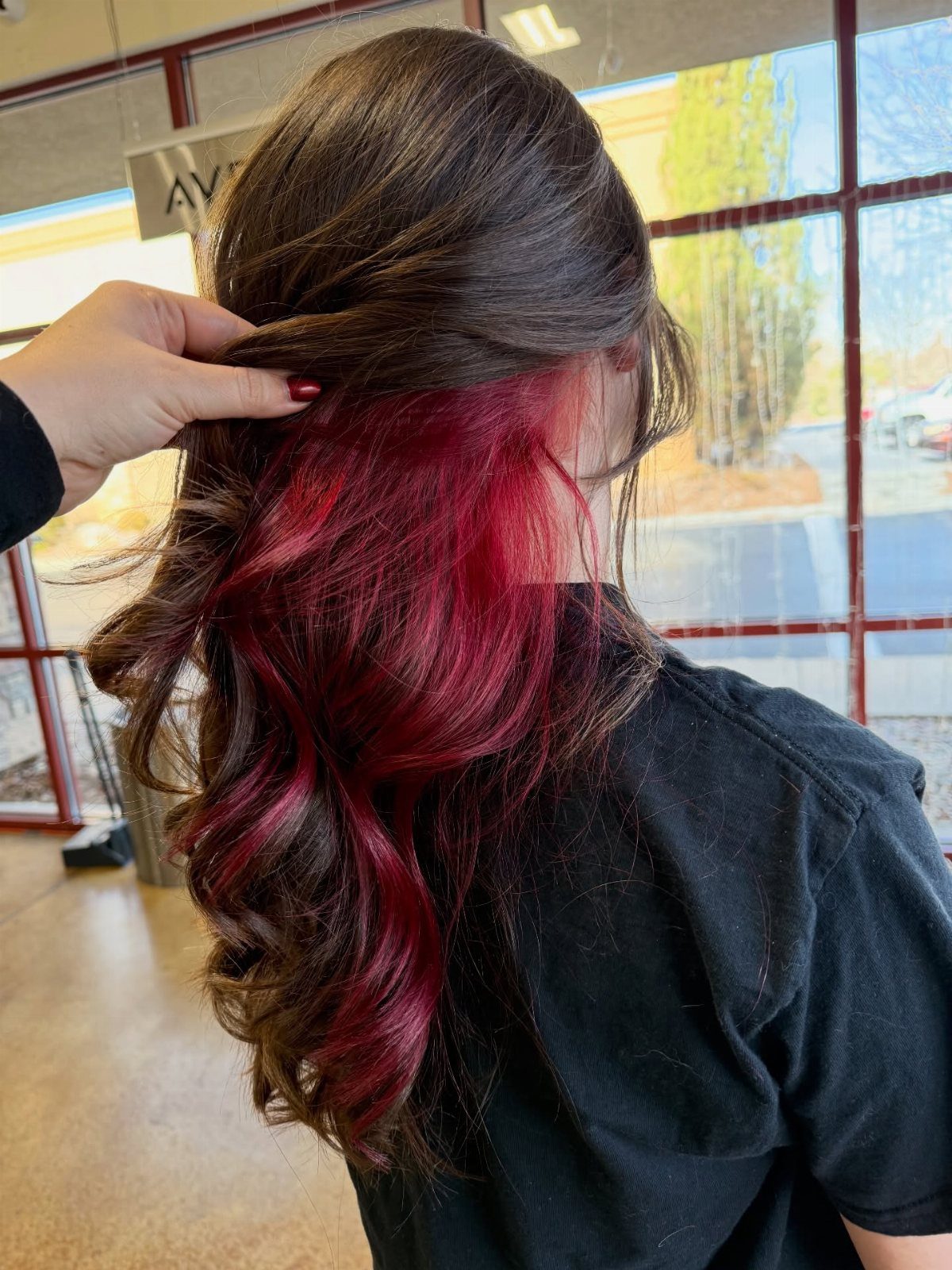 Dark brown hair lifted to reveal vivid red peekaboo color underneath