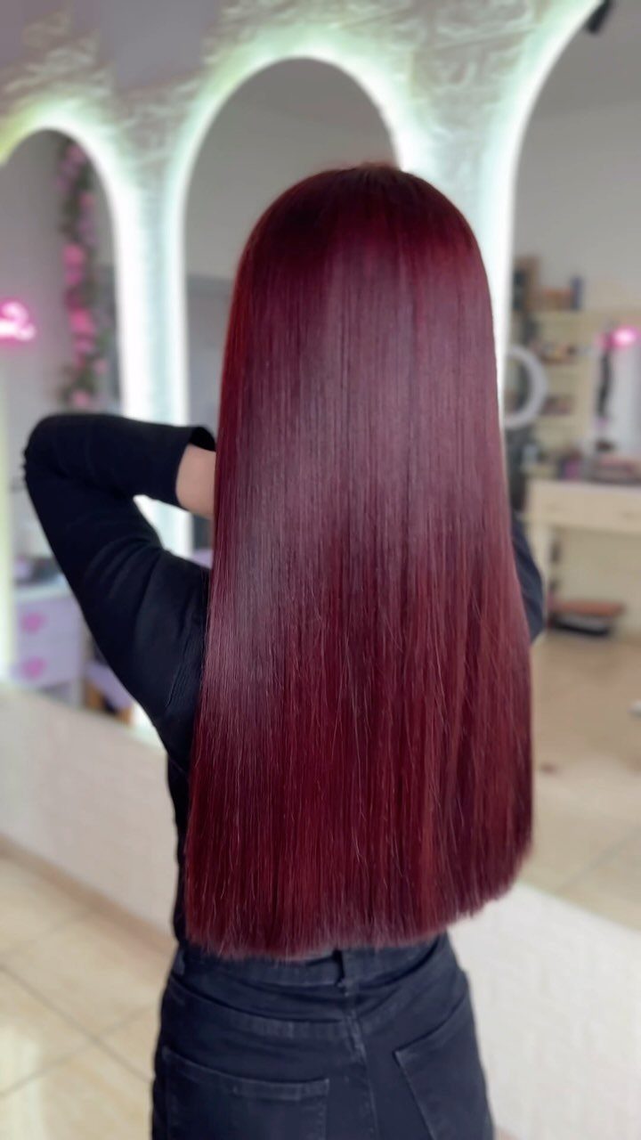 Long, glossy vivid plum hair shown from behind in a bright salon