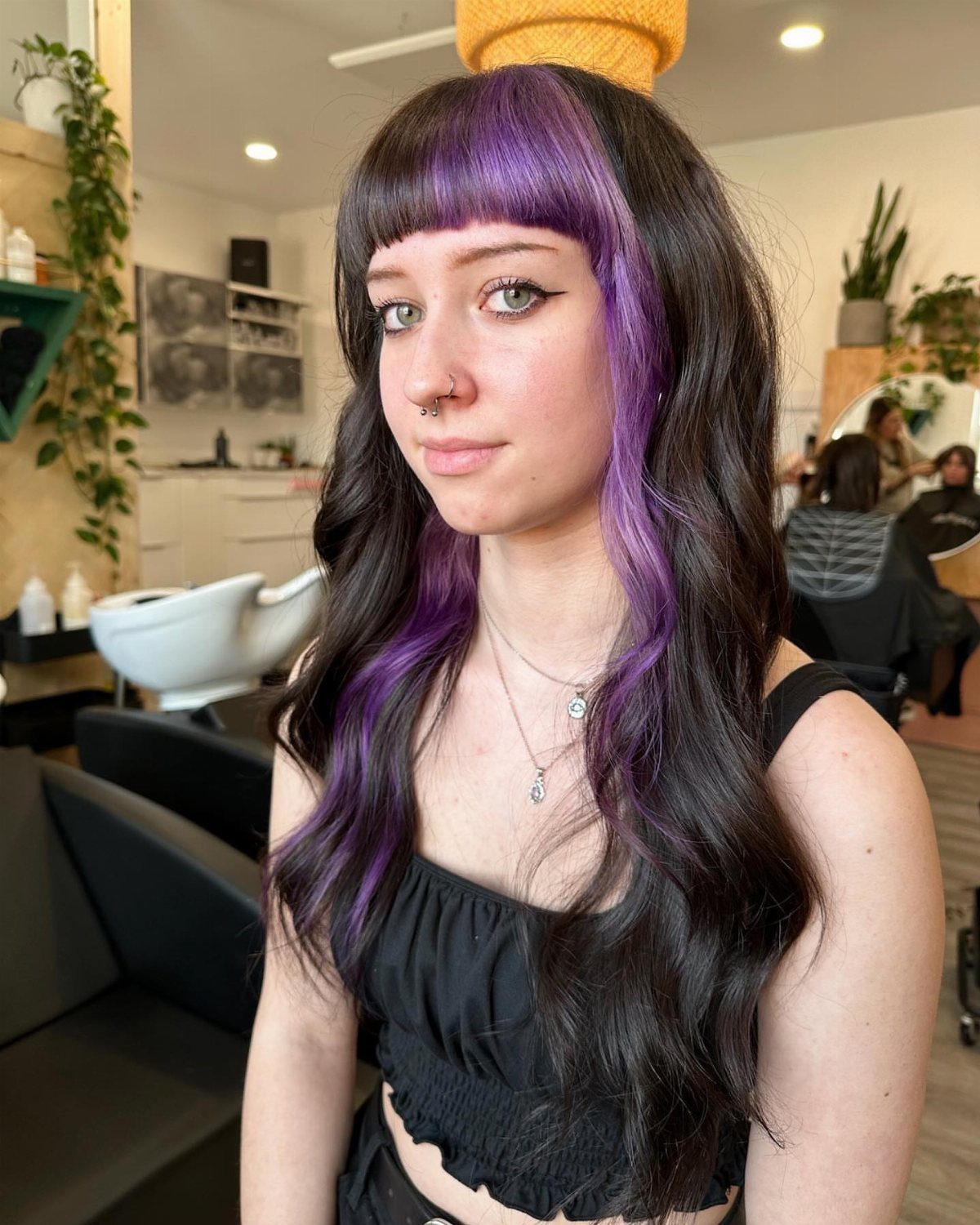Woman with vivid purple bangs and face-framing sections in a salon