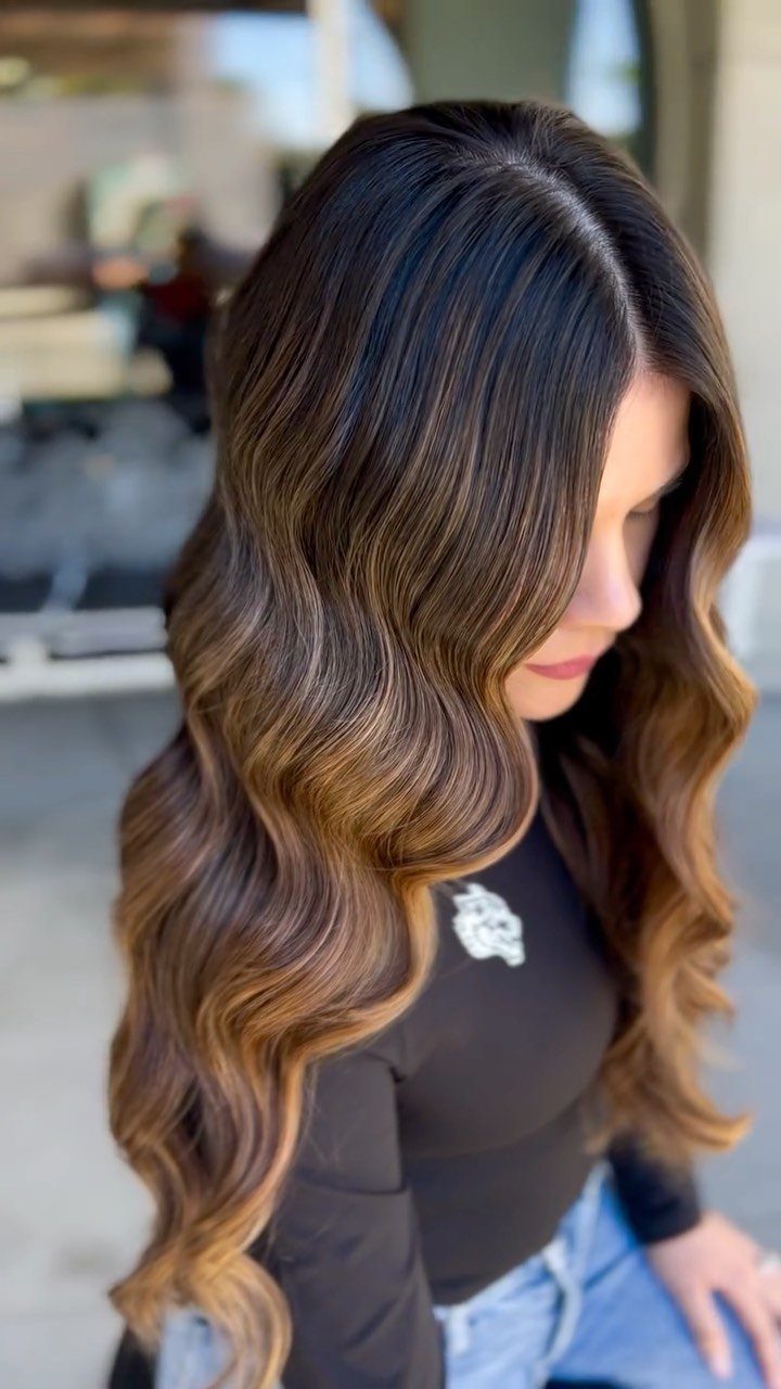 Woman with long wavy brown hair showing blended caramel balayage tones