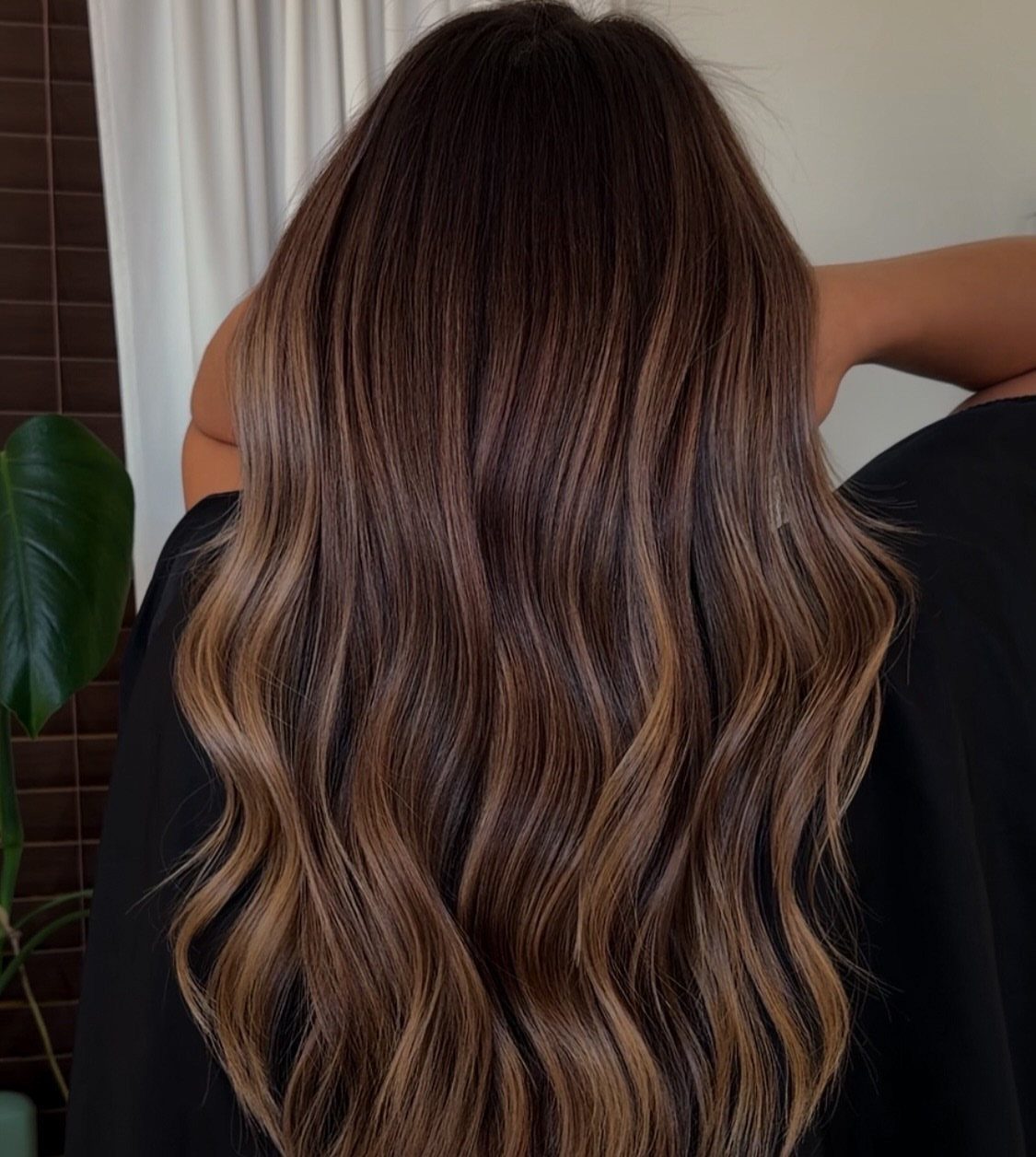 Long wavy brunette hair with caramel highlights shown from behind