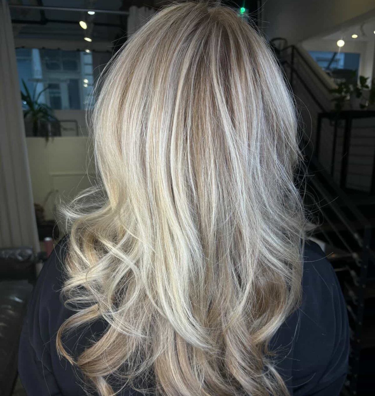 Long blonde hair with blended highlights and loose curls from behind