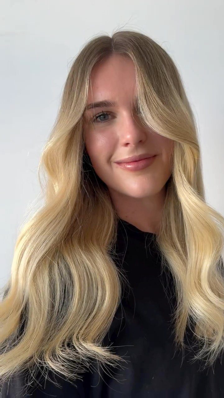 Woman with long, wavy, creamy blonde hair wearing a black top