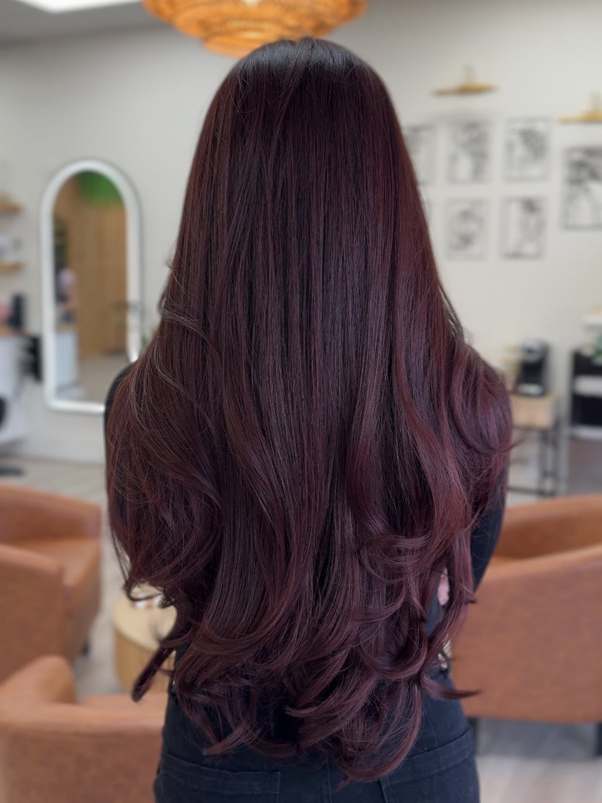 Long chocolate cherry hair with glossy burgundy-red waves in a salon