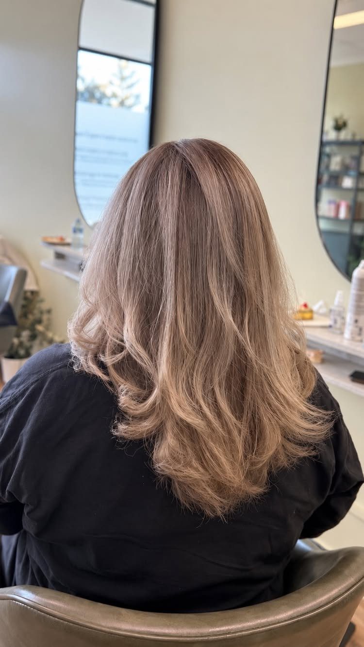 Layered cool ash-blonde hair with curled ends in a salon chair