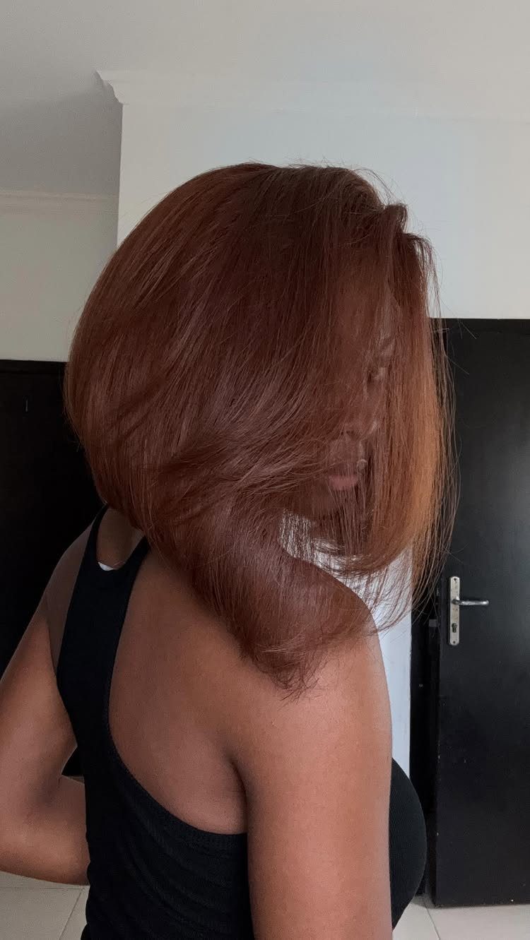Shoulder-length reddish-brown hair with warm copper tones, shown from the side