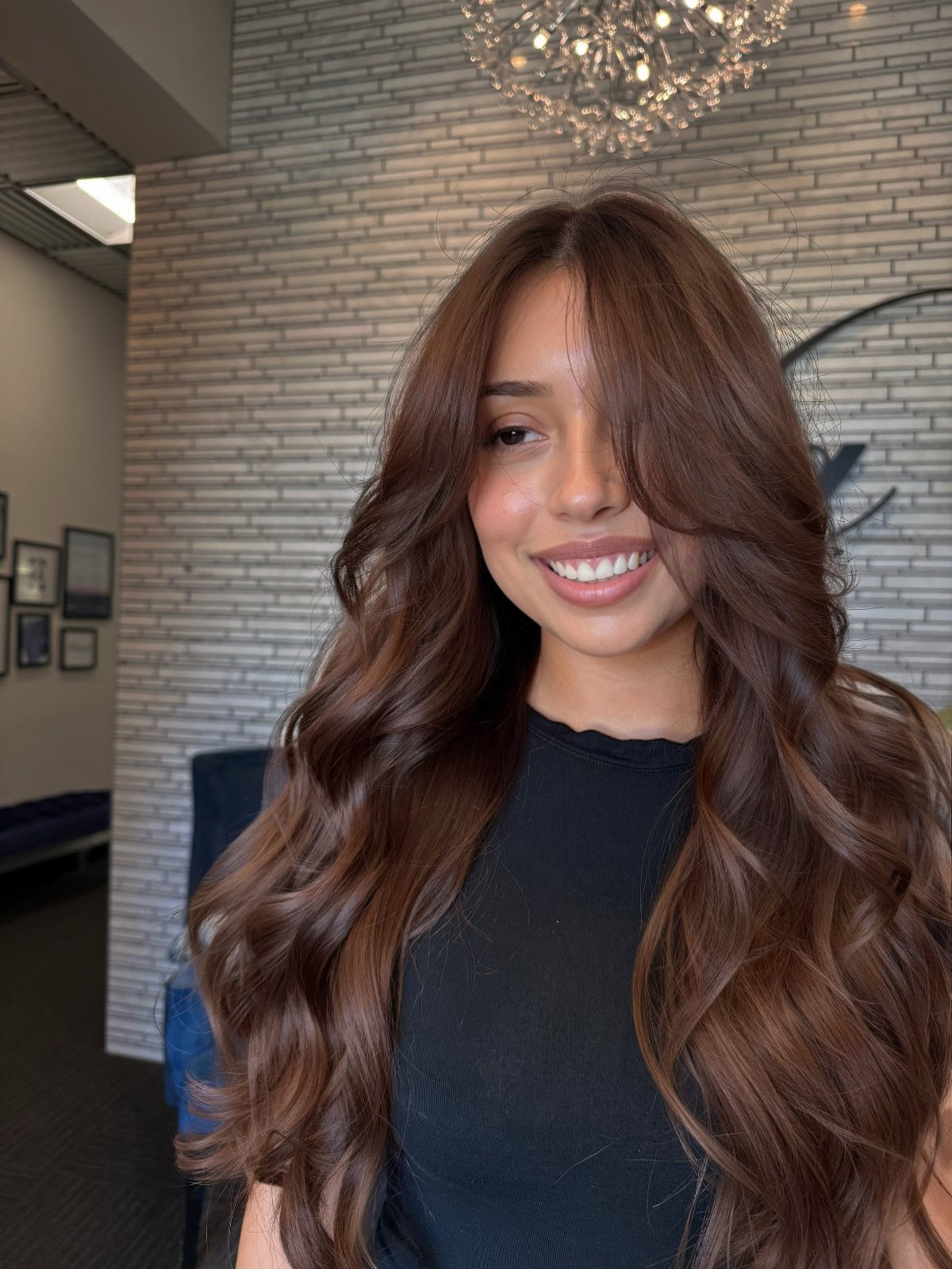 Woman with long, glossy dark chocolate-brown hair standing in a salon